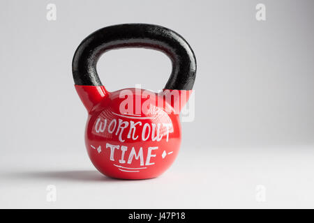 Red kettlebell con tempo di allenamento caratteri scritti su di esso isolato su bianco con spazio di copia Foto Stock