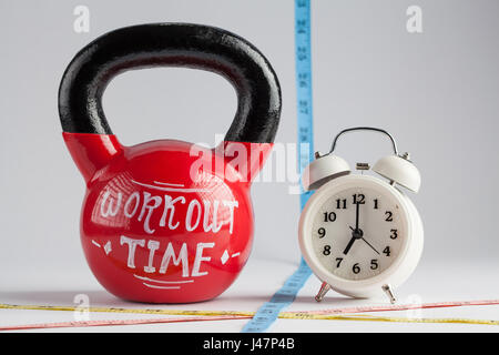 Red kettlebell con tempo di allenamento di scritte, tradizionale sveglia e nastro di misurazione isolata su bianco con copia spazio. Il tempo di lavorare fuori, salutare l Foto Stock