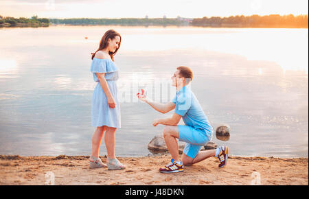 Proposta di matrimonio su sunset . giovane fa una proposta di fidanzamento per la sua ragazza sulla spiaggia Foto Stock