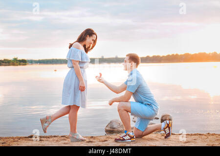 Proposta di matrimonio su sunset . giovane fa una proposta di fidanzamento per la sua ragazza sulla spiaggia Foto Stock