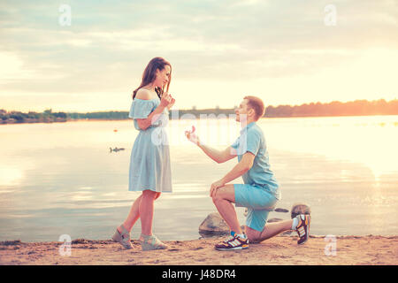 Proposta di matrimonio su sunset . giovane fa una proposta di fidanzamento per la sua ragazza sulla spiaggia Foto Stock