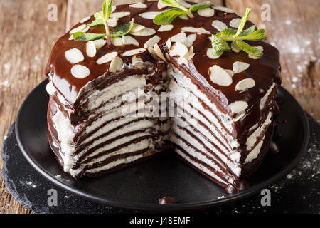 Dolce casalingo affettato crepes al cioccolato torta con panna montata e mandorle close-up su una piastra orizzontale. Foto Stock