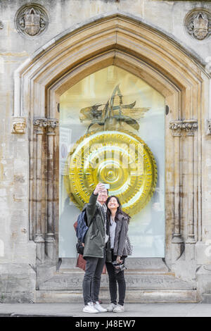 Turisti cinesi giovane prendere una fotografia selfie davanti alla chronophage (tempo-eater) e grande orologio disegnato da John Taylor al di fuori del Corpus Ch Foto Stock