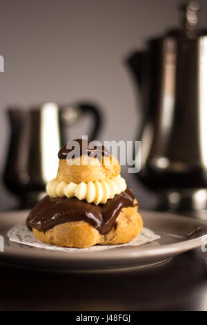 Primo piano di una crema di cioccolato pasta sfoglia con un set di argento di caffè e latte Foto Stock