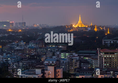 Edifici di appartamenti e di lit Shwedagon pagoda in Yangon, Myanmar, visto da sopra la sera. Foto Stock