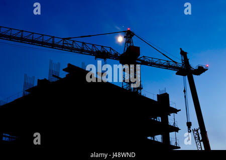 Sito in costruzione. Industrial gru per edilizia e costruzione di sagome sul cielo notturno. Bella colorato paesaggio notturno. Foto Stock