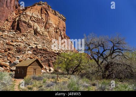 Vintage Historic Mormon Settlers Rustic Wooden Log Cabin School. Fruita, Capitol Reef National Park, con lo scenico paesaggio delle Red Rock dello Utah il giorno del sole Foto Stock