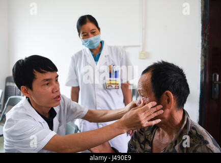 Wuzhishan, cinese della provincia di Hainan. Il 10 maggio, 2017. Medico egli Wenyi (L) gli esami per il 66-anno-vecchio abitante Wang Maohua nel villaggio Maozu Wuzhishan in città, a sud della Cina di Hainan Provincia, 10 maggio 2017. A partire dal mese di aprile il personale medico di Oftalmologia Wuzhishan Hospital sono venuti a villaggi di Fanyang Township fornire gratuitamente gli esami degli occhi per gli anziani. Fino a mercoledì, 350 anziani del villaggio aveva ricevuto gli esami e sono stati offerti suggerimenti di trattamento. Credito: Shen Hong/Xinhua/Alamy Live News Foto Stock