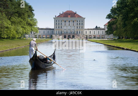 Monaco di Baviera, Germania. Xi Apr, 2017. Un gondoliere con la sua Gondola Veneziana e due passeggeri passa scivola sulle acque del canale centrale nella parte anteriore del paesaggio del palazzo di Nymphenburg a Monaco di Baviera, Germania, 11 aprile 2017. I visitatori al palazzo possono cavalcare su originale gondole veneziane durante l'estate, in commemorazione del veneto magnifica navi della corte del principe elettore Max Emanuel. Foto: Peter Kneffel/dpa/Alamy Live News Foto Stock