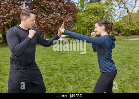 L'uomo boxe con Personal Trainer presso il parco Foto Stock