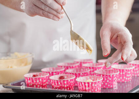 Versando Cake Mix in lievito muffin vassoio Foto Stock