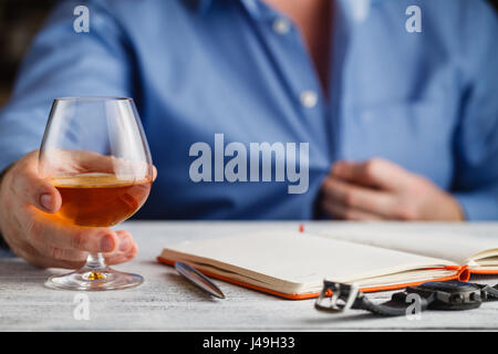 Imprenditore maturo con in mano un bicchiere di whisky in hotel Foto Stock