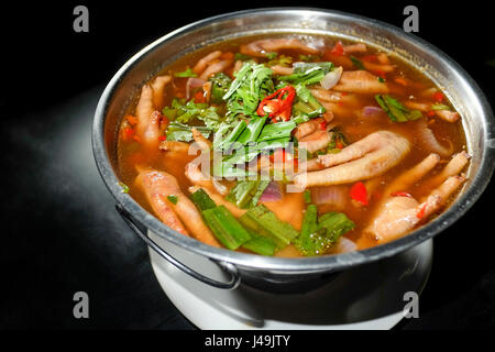 Zuppa piccante piede di pollo nella ciotola calda e sfondo nero Foto Stock