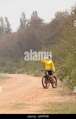 Bicicletta di montagna uomo di bere acqua fresca da bottiglia su sterrato Foto Stock
