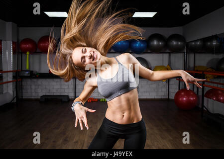 Slim giovane ragazza fitness con lunghi capelli ondulati nel club salute. Sorridente ragazza caucasica nel centro fitness. Foto Stock