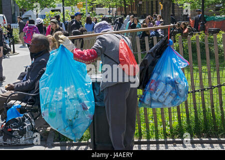 Un'anziana donna asiatica la raccolta di lattine e bottiglie dal cestino per contanti in per depositare il denaro. In Washington Square Park a Manhattan, New York City. Foto Stock