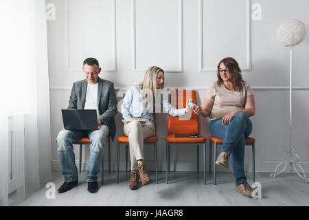 Un gruppo di giovani creativi seduti su sedie in sala d'attesa Foto Stock