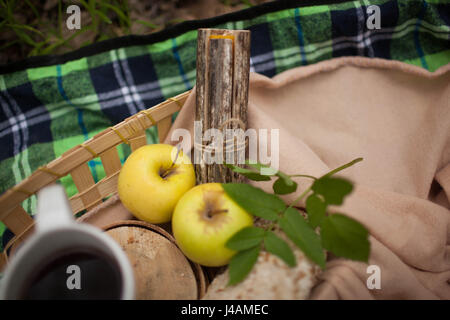 La tazza di tè e due mele giacciono sulla coperta Foto Stock