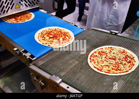 Il convogliatore per pizza making. La fase di aggiunta di formaggio Foto Stock