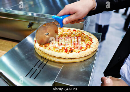 Uomo in una tuta taglia una pizza Foto Stock