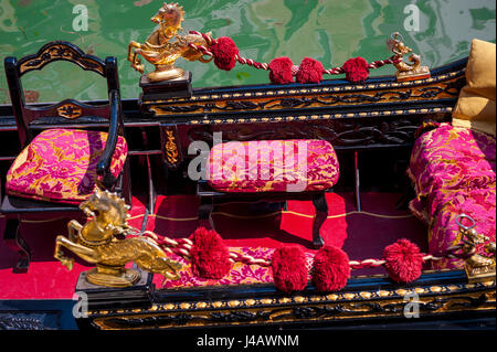 Close-up dettaglio di un tradizionale gondola veneziana con una decorazione di felpa rossa attesa di posti a sedere per i clienti su un canale di Venezia, Italia Foto Stock