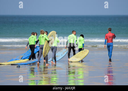 Una scuola di surf istruttore è a capo di un gruppo di novizi di surf fuga Scuola Surf Fistral Beach Newquay Cornwall Surf Surfers ai partecipanti Foto Stock