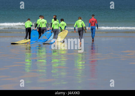 Una scuola di surf istruttore è a capo di un gruppo di novizi di surf fuga Scuola Surf Fistral Beach Newquay Cornwall Surf Surfers ai partecipanti Foto Stock