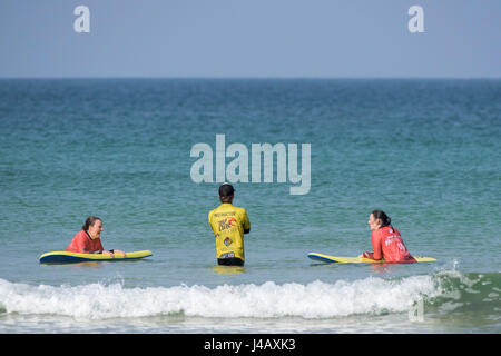 Una scuola di surf istruttore insegnamento novizi Fistral Beach Newquay Cornwall Surf Surf Surf coach allievo istruttore di apprendimento aiutando Foto Stock