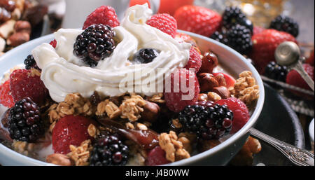 Vista di una colazione a base di cereali con bacche e frutti secchi, di latte e di panna montata Foto Stock