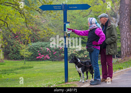 Giovane con cane controllo mappa dei giardini sul cartello a Exbury Gardens, New Forest National Park, Hampshire nel maggio molla Foto Stock