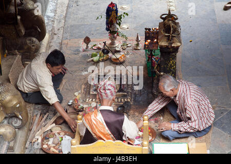 Tre uomini facendo Offerte e preghiere per il Buddha il compleanno nel Tempio d'Oro - Hiranyavarna Mahavihara - Patan, o Lalitpur, Kathmandu, Nepal Foto Stock