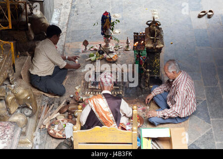 Tre uomini facendo Offerte e preghiere per il Buddha il compleanno nel Tempio d'Oro - Hiranyavarna Mahavihara - Patan, o Lalitpur, Kathmandu, Nepal Foto Stock