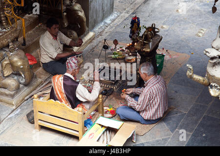 Tre uomini facendo Offerte e preghiere per il Buddha il compleanno nel Tempio d'Oro - Hiranyavarna Mahavihara - Patan, o Lalitpur, Kathmandu, Nepal Foto Stock