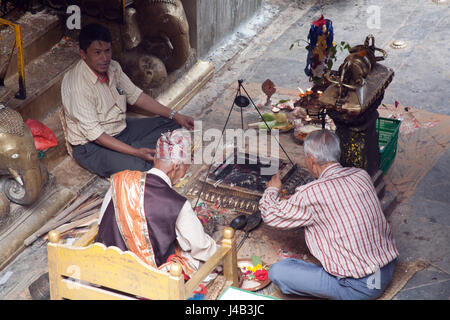 Tre uomini facendo Offerte e preghiere per il Buddha il compleanno nel Tempio d'Oro - Hiranyavarna Mahavihara - Patan, o Lalitpur, Kathmandu, Nepal Foto Stock