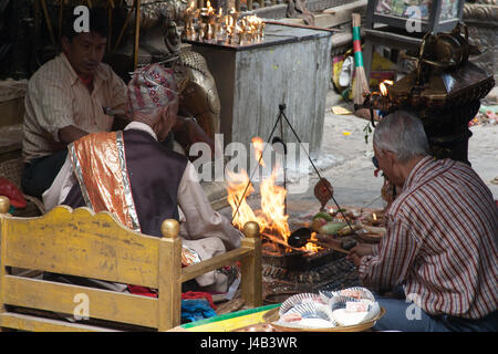 Tre uomini facendo Offerte e preghiere per il Buddha il compleanno nel Tempio d'Oro - Hiranyavarna Mahavihara - Patan, o Lalitpur, Kathmandu, Nepal Foto Stock