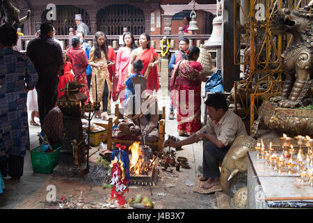 Tre uomini facendo Offerte e preghiere per il Buddha il compleanno nel Tempio d'Oro - Hiranyavarna Mahavihara - Patan, o Lalitpur, Kathmandu, Nepal Foto Stock