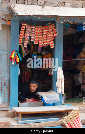 Disabilitato proprietario del negozio è in attesa per i clienti, distesa sul suo ventre. Bhaktapur, Nepal. Foto Stock