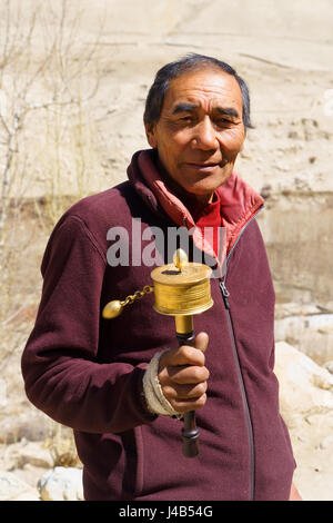 Uomo nepalese ruotando la sua preghiera ruota. Foto Stock