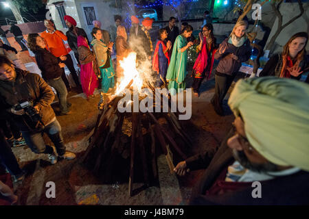 Gli ospiti ballare, cantare e applaudire intorno al falò presso la celebrazione Lohri in Punjab (India). Foto Stock