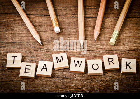 Il lavoro di squadra parola scritta sul blocco di legno con matite di legno su sfondo di legno. Foto Stock