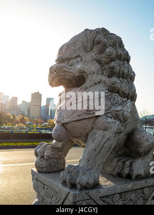 Foo cane (Cinese Lion Guard) Guardando oltre lo skyline di Vancouver durante il tramonto Foto Stock