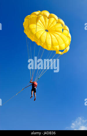 Paracadutista sul paracadute gialli nella soleggiata cielo blu. Uno stile di vita attivo. Sport estremo. Foto Stock