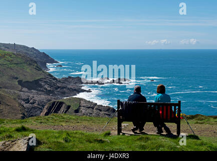 Giovane seduto su un banco di lavoro, che guarda al mare, Penwith, Cornwall, England Regno Unito Foto Stock