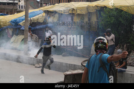 Srinagar Kashmir. Il 12 maggio 2017. .Un manifestante Kashmir getta esplosa posteriore gas lacrimogeni shell. Scontri scoppiati tra dimostranti e forze di sicurezza in downtown area Nowhatta di Srinagar. Gruppi di giovani si concedeva sloganeering e pietra- della concia a forze di sicurezza indiane subito dopo Venerdì preghiere congregazionale. Secondo la relazione, 102 civili disarmati sono stati uccisi in 135 giorni di disordini che è stato scatenato dalla uccisione di luglio 8 di Hizbul Mujahideen comandante Burhan Wani dalle forze armate. Credito: sofi suhail/Alamy Live News Foto Stock