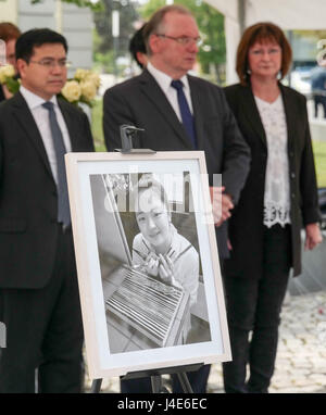 Dessau-Rosslau, Germania. Il 12 maggio 2017. Premier della Sassonia-Anhalt Reiner Haseloff (c, CDU) in piedi con la moglie Gabriele Blumen e l'ambasciata cinese consigliere, Qinghua Zhao, dietro una foto di Yangjie Li, un Cinese studente di architettura che è stata violentata e uccisa un anno fa, in corrispondenza di un evento commemorativo in Dessau-Rosslau, Germania, 12 maggio 2017. Foto: Peter Endig/dpa-Zentralbild/dpa/Alamy Live News Foto Stock