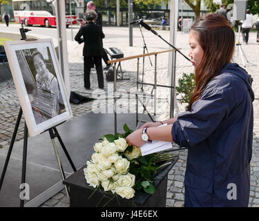 Dessau-Rosslau, Germania. Il 12 maggio 2017. Uno studente stabilisce i fiori da una foto di Yangjie Li, un Cinese studente di architettura che è stata violentata e uccisa un anno fa, in corrispondenza di un evento commemorativo in Dessau-Rosslau, Germania, 12 maggio 2017. Foto: Peter Endig/dpa-Zentralbild/dpa/Alamy Live News Foto Stock