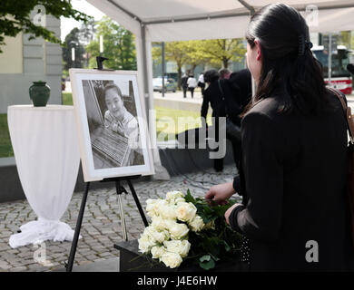 Dessau-Rosslau, Germania. Il 12 maggio 2017. Uno studente stabilisce i fiori da una foto di Yangjie Li, un Cinese studente di architettura che è stata violentata e uccisa un anno fa, in corrispondenza di un evento commemorativo in Dessau-Rosslau, Germania, 12 maggio 2017. Foto: Peter Endig/dpa-Zentralbild/dpa/Alamy Live News Foto Stock