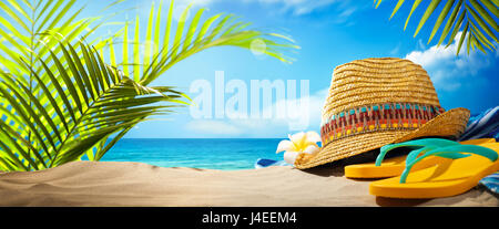 Cappello di paglia e flip flop sulla spiaggia Foto Stock