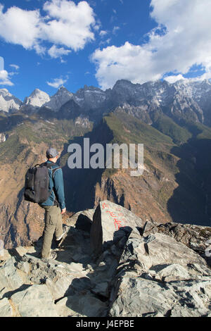 L'uomo escursionismo in Tiger che saltava Gorge, UNESCO, con Jade Dragon Snow Mountain (Yulong Xueshan), Yunnan, Cina Foto Stock