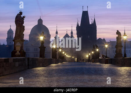 Street lanterne e vecchie statue telaio gli edifici storici sul Ponte Carlo all'alba, UNESCO, Praga, Repubblica Ceca Foto Stock